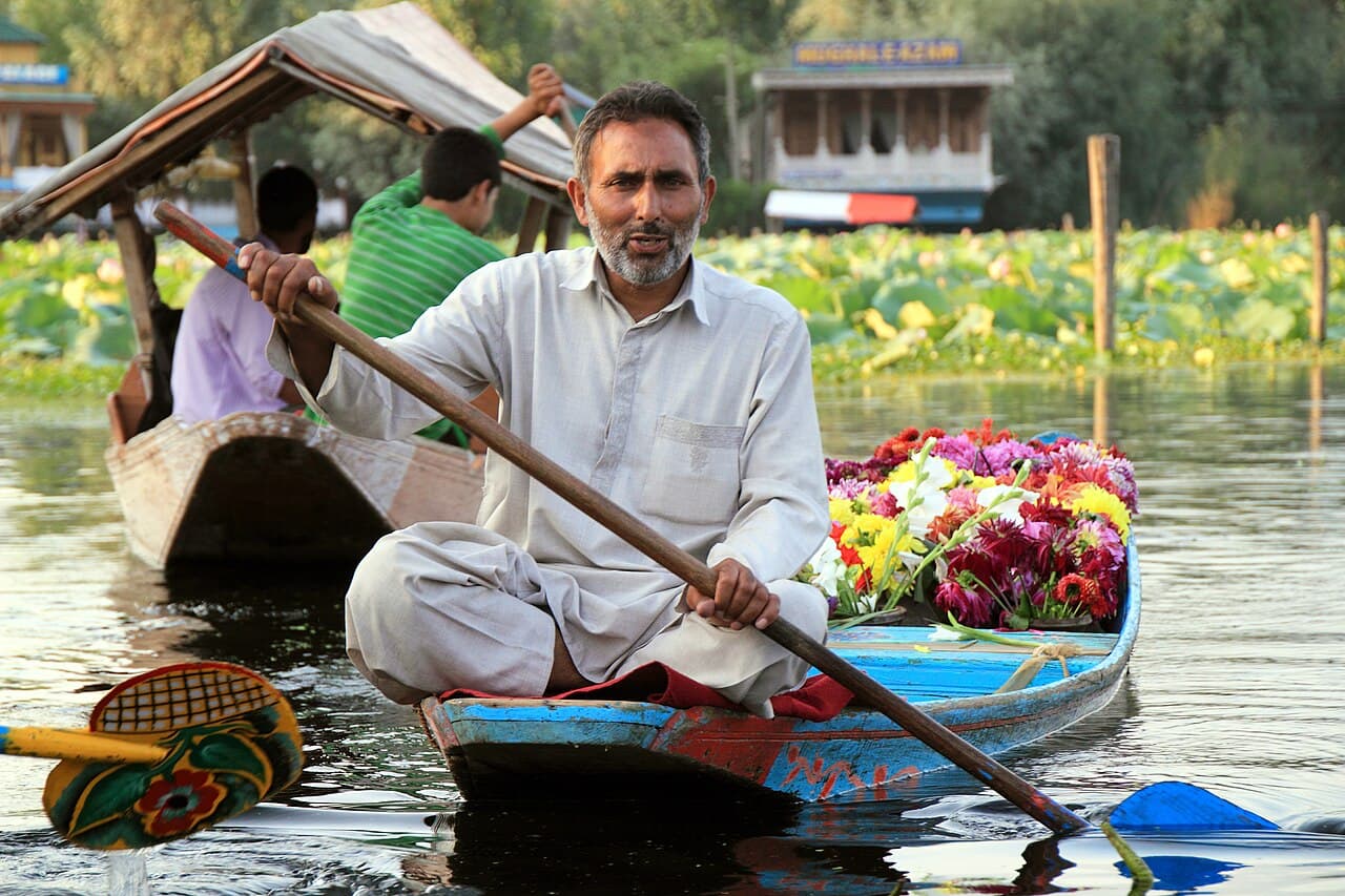 A flower seller paddling between houseboats on Dal Lake